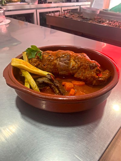 Muslos rellenos bañados en salsa con guarnición de patatas fritas.