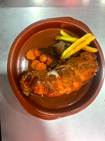 Muslos rellenos bañados en salsa con guarnición de patatas fritas.